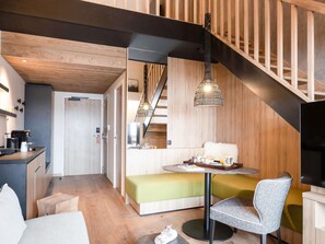 A modern interior with a staircase, a dining area, and a kitchenette.