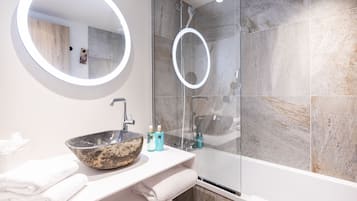 A modern bathroom with a round mirror, a large sink, and a glass-enclosed shower.
