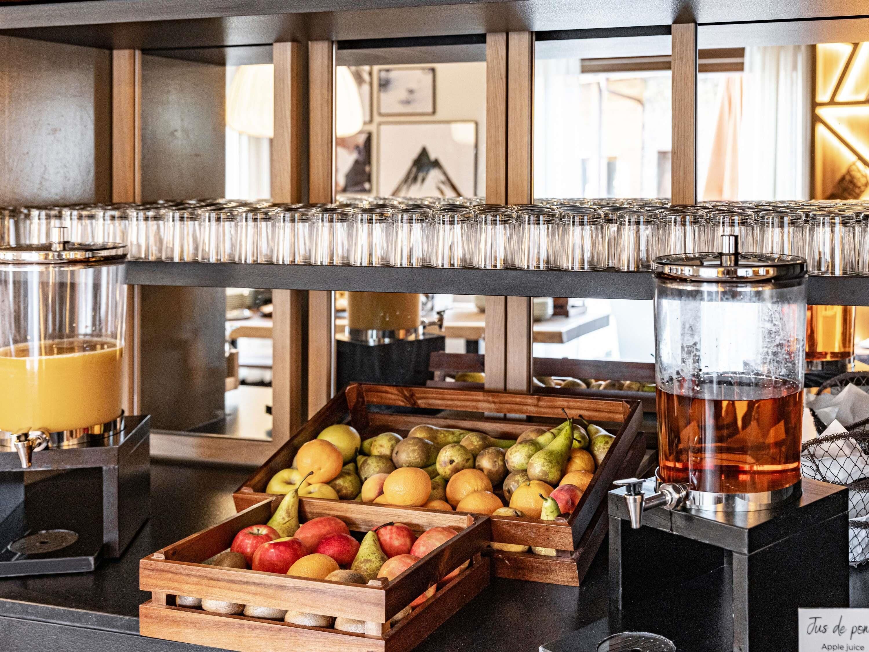 Een ontbijtbuffet met fruitkisten, een koffieapparaat en een theedispenser.