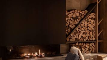 Un salon moderne avec une cheminée, une pile de bois de chauffage et un coin salon confortable.