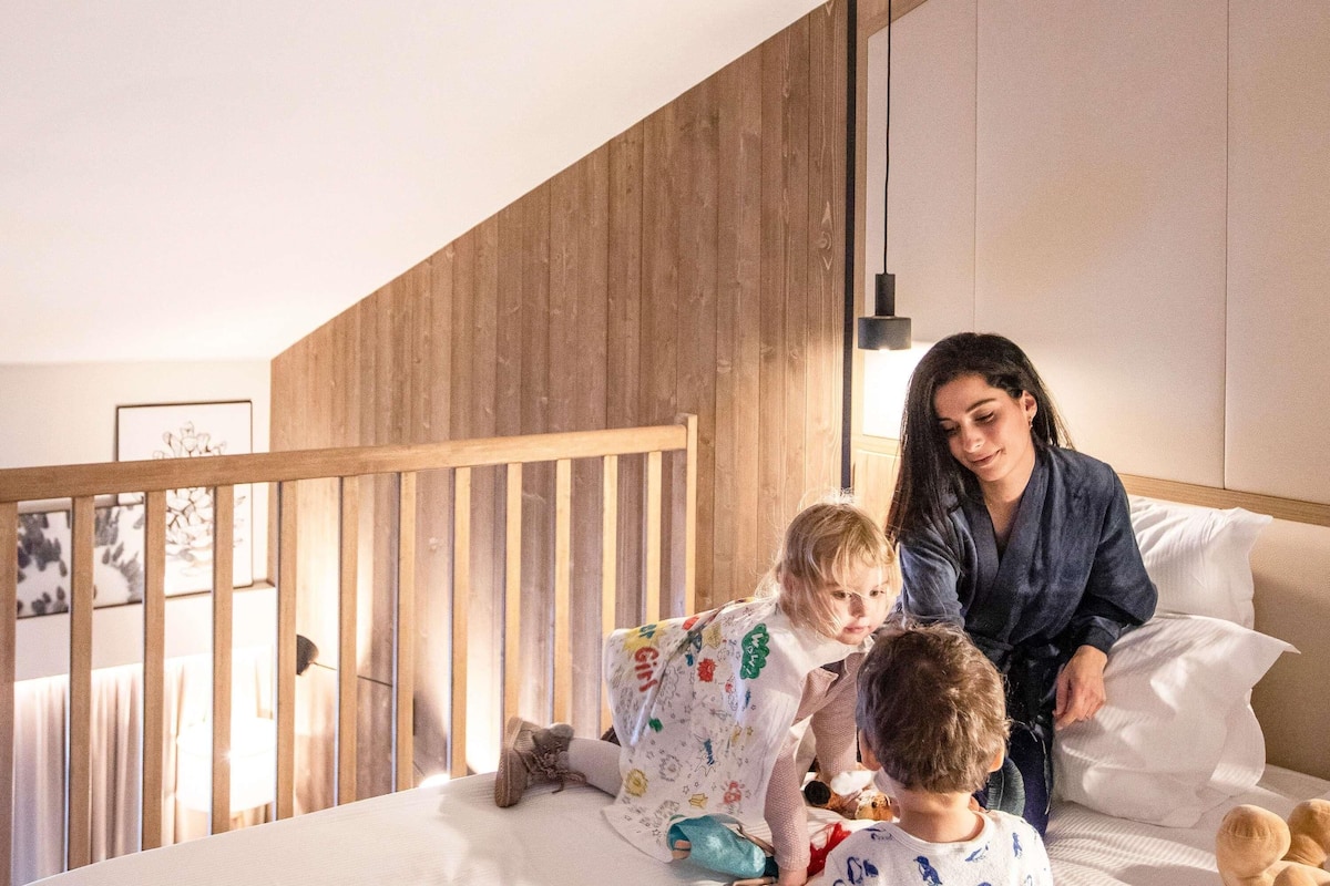 A bedroom with a wooden slat wall, a bed with pillows, and a bedside table.