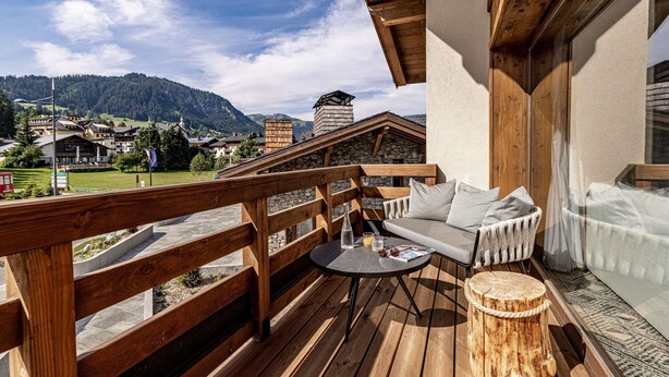 Une terrasse en bois avec un canapé et une table, offrant une vue sur un paysage montagneux.