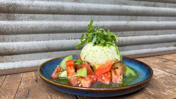 Une assiette en céramique bleue contenant un œuf poché, des légumes et une garniture.