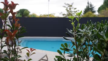 Una piscina al aire libre de temporada, sombrillas