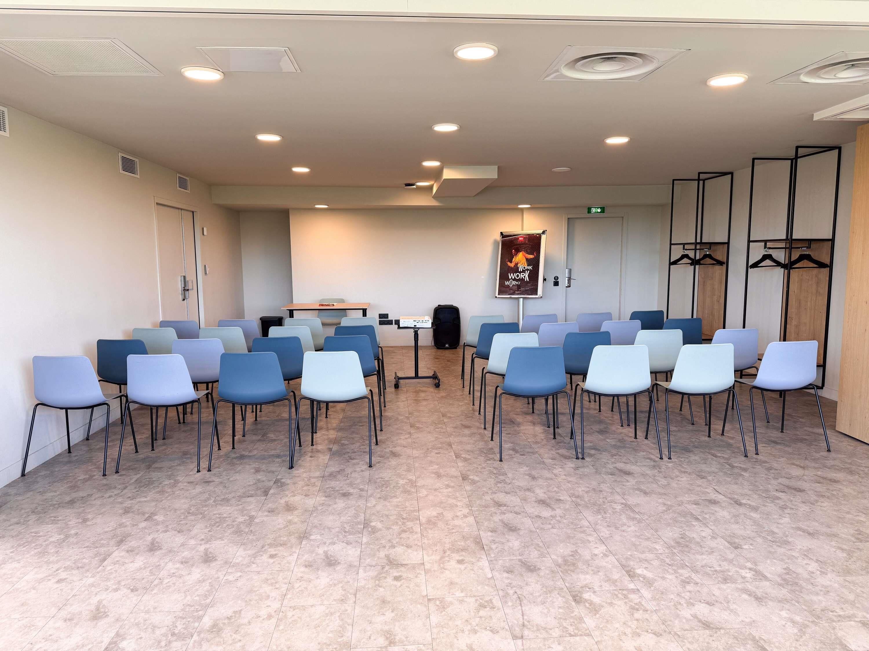 A conference room with rows of chairs, a table, and a projector screen.