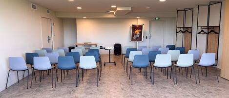 A conference room with rows of chairs, a table, and a projector screen.