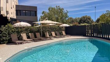 Una piscina al aire libre de temporada, sombrillas