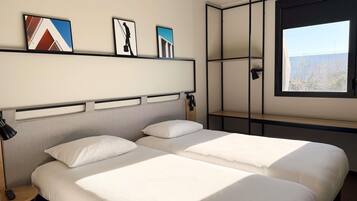 Ein Hotelzimmer mit zwei Betten, einem Fenster und Bildern an der Wand.