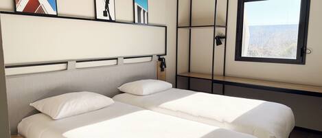 Una habitación de hotel con dos camas, un ventanal grande y obras de arte en la pared.