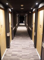Pasillo de hotel con puertas numeradas del 101 al 102, suelo alfombrado e iluminación empotrada.