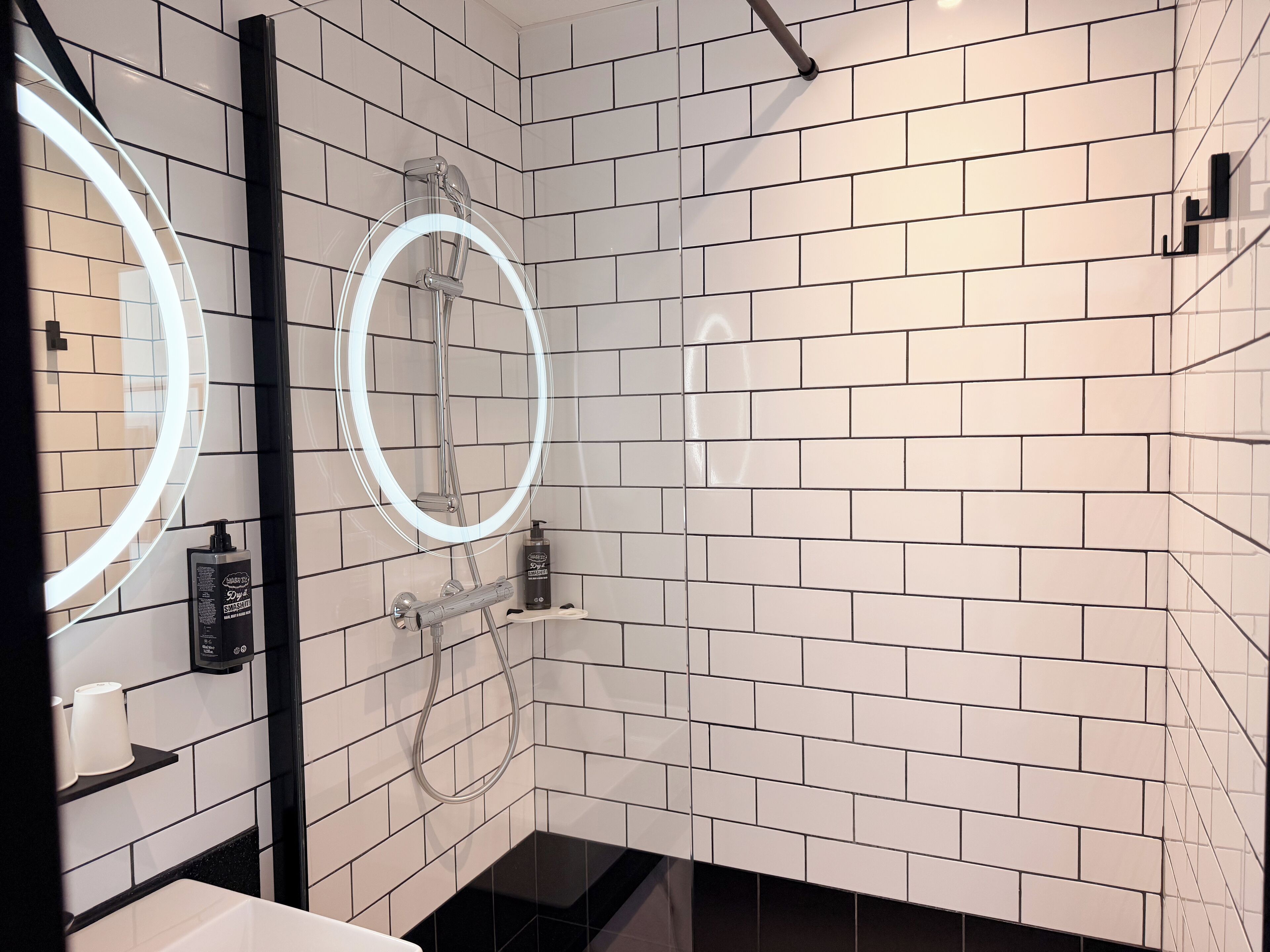 A modern bathroom with white subway tiles, a glass shower enclosure, and a handheld showerhead.