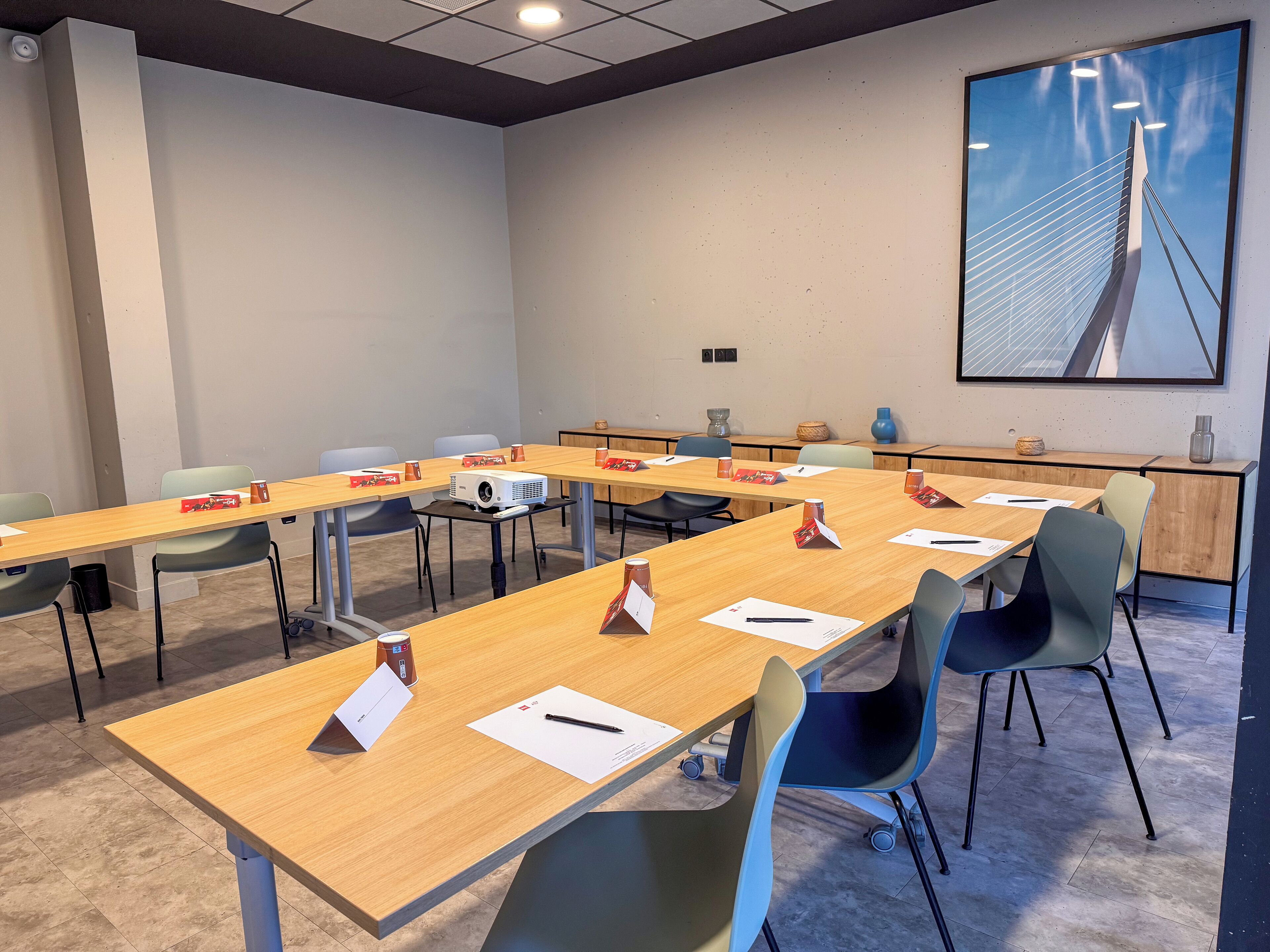A conference room with long tables, chairs, and a projector.