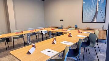 A conference room with long tables, chairs, and a projector.