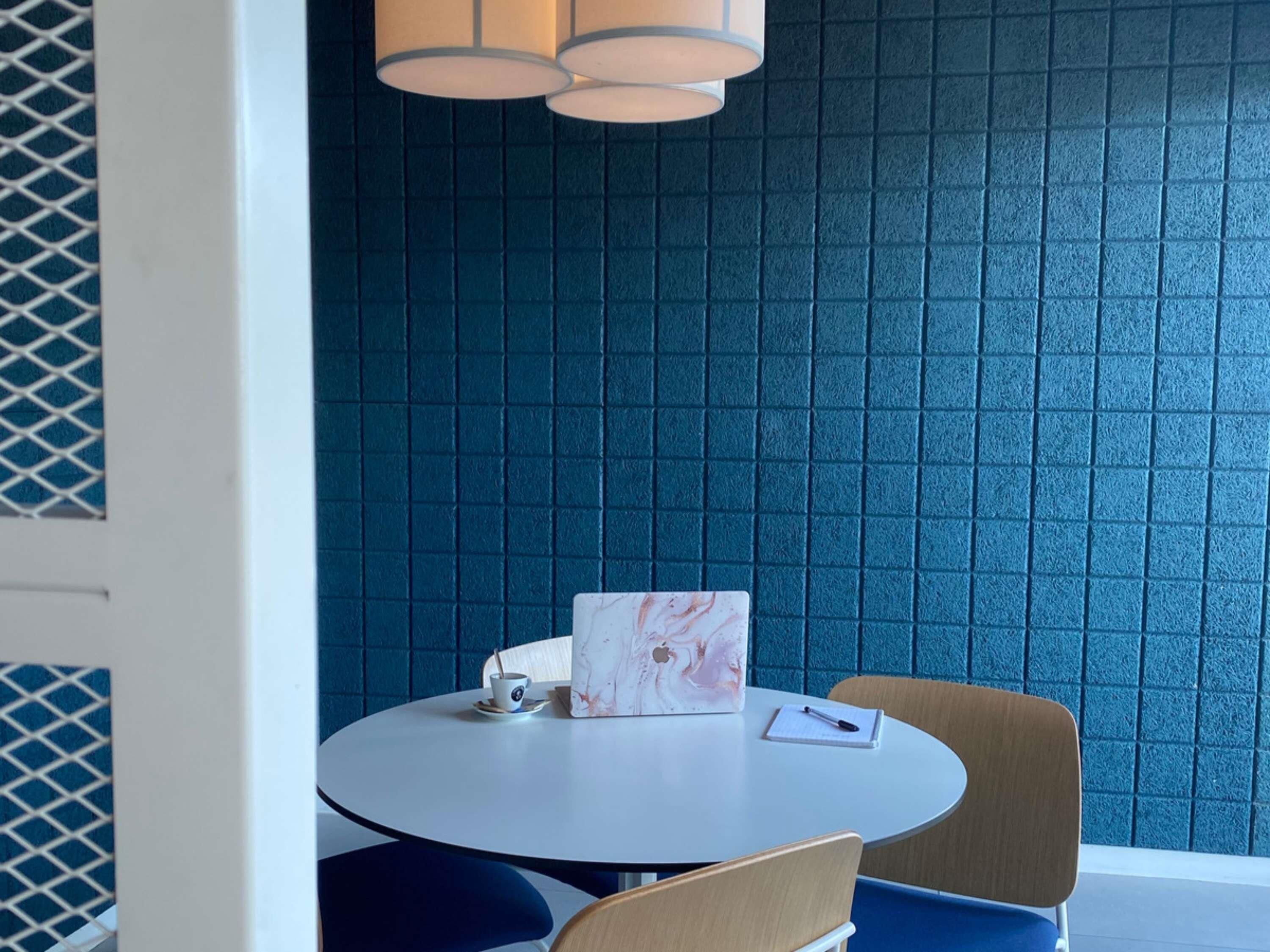 Une table ronde avec un ordinateur portable, une tasse et un carnet.