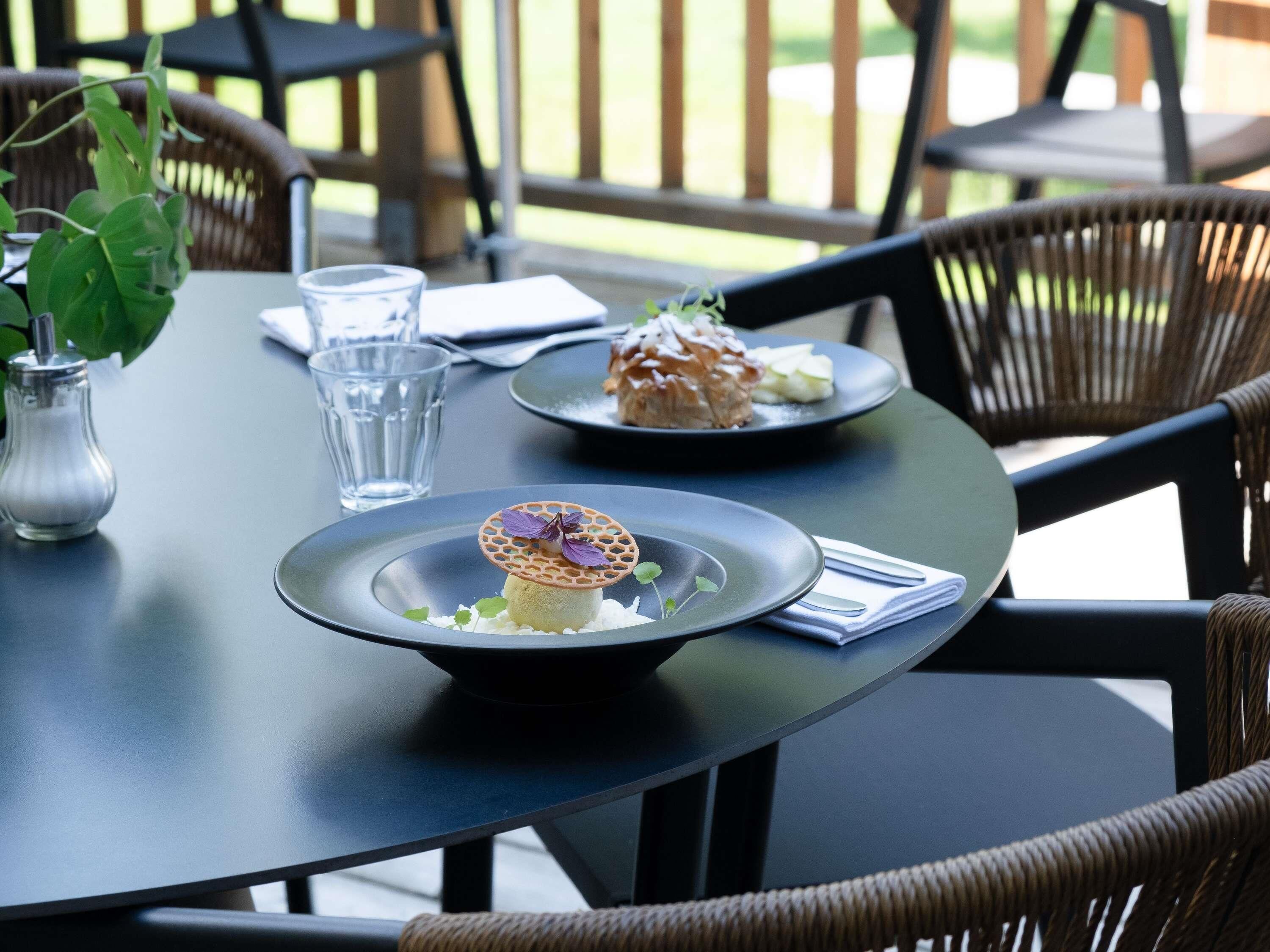 A dining table with a plate of food, a glass of water, and a small vase.