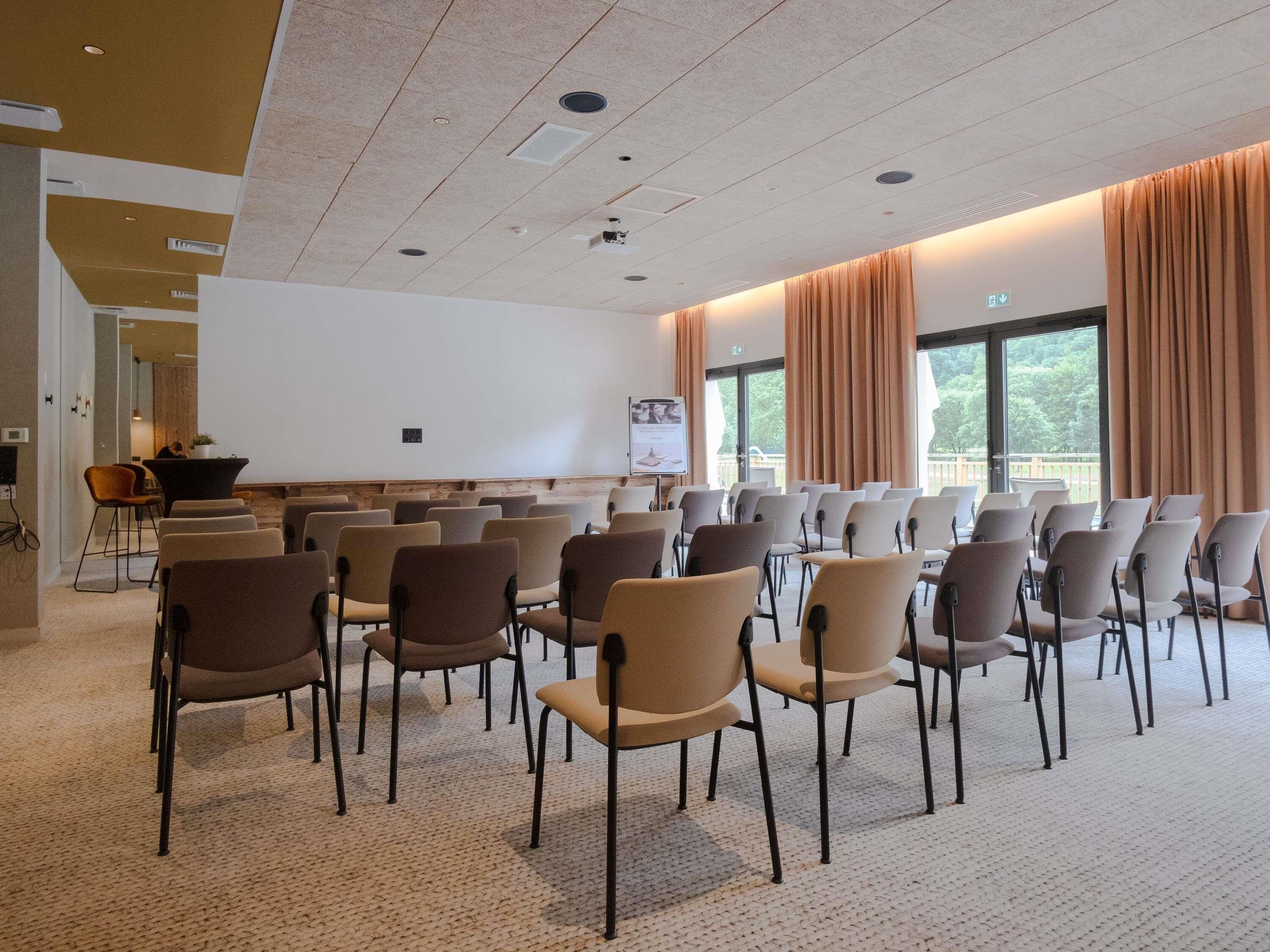 A conference room with rows of chairs, a whiteboard, and a projection screen.