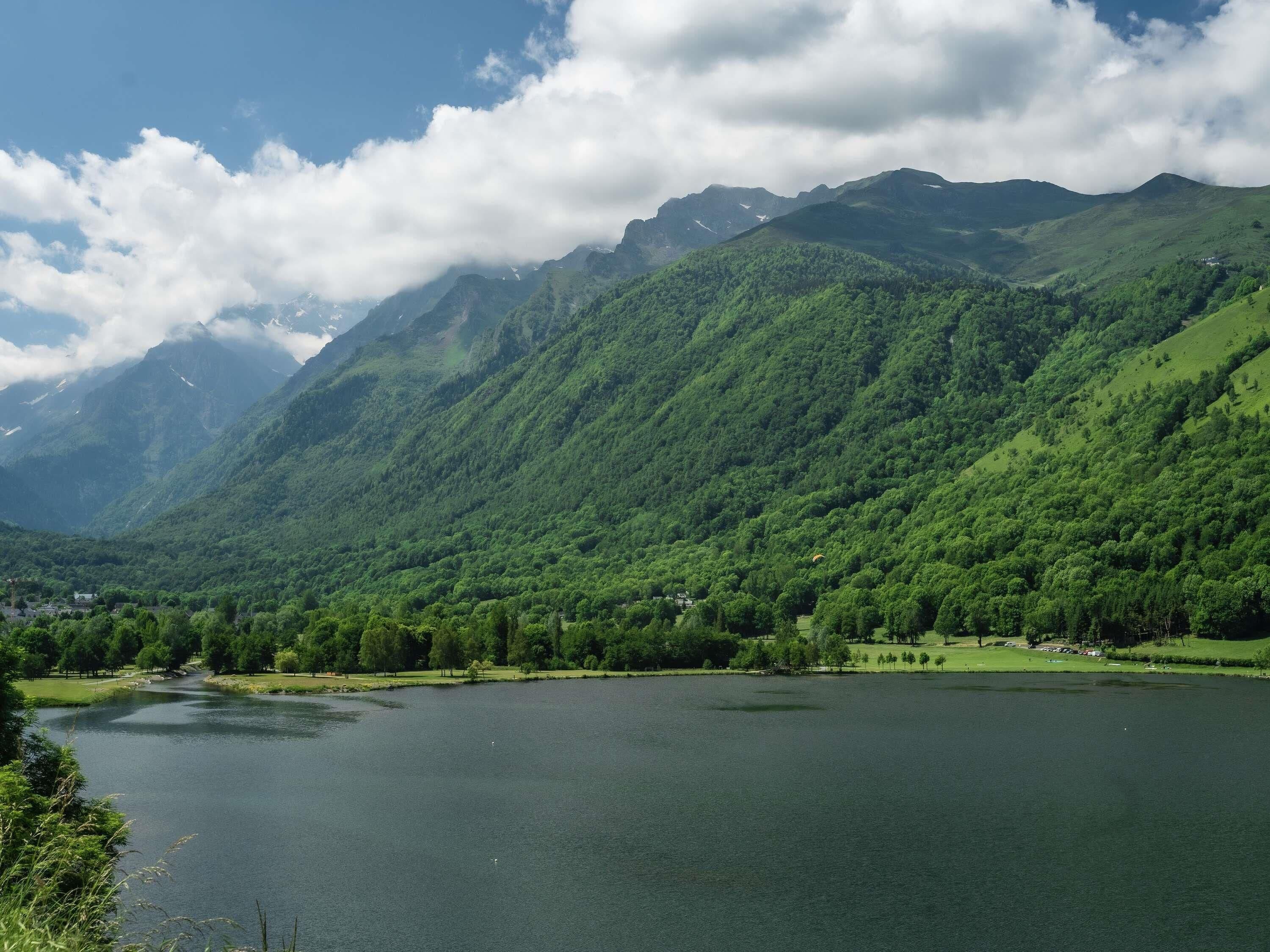 Eine Berglandschaft mit einem See, Bäumen und einer kleinen Siedlung.