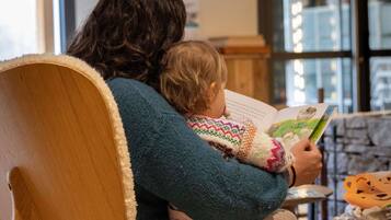 Iemand zit op een houten stoel en leest een boek.