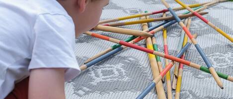 A child playing with colorful pencils on a patterned mat outdoors.