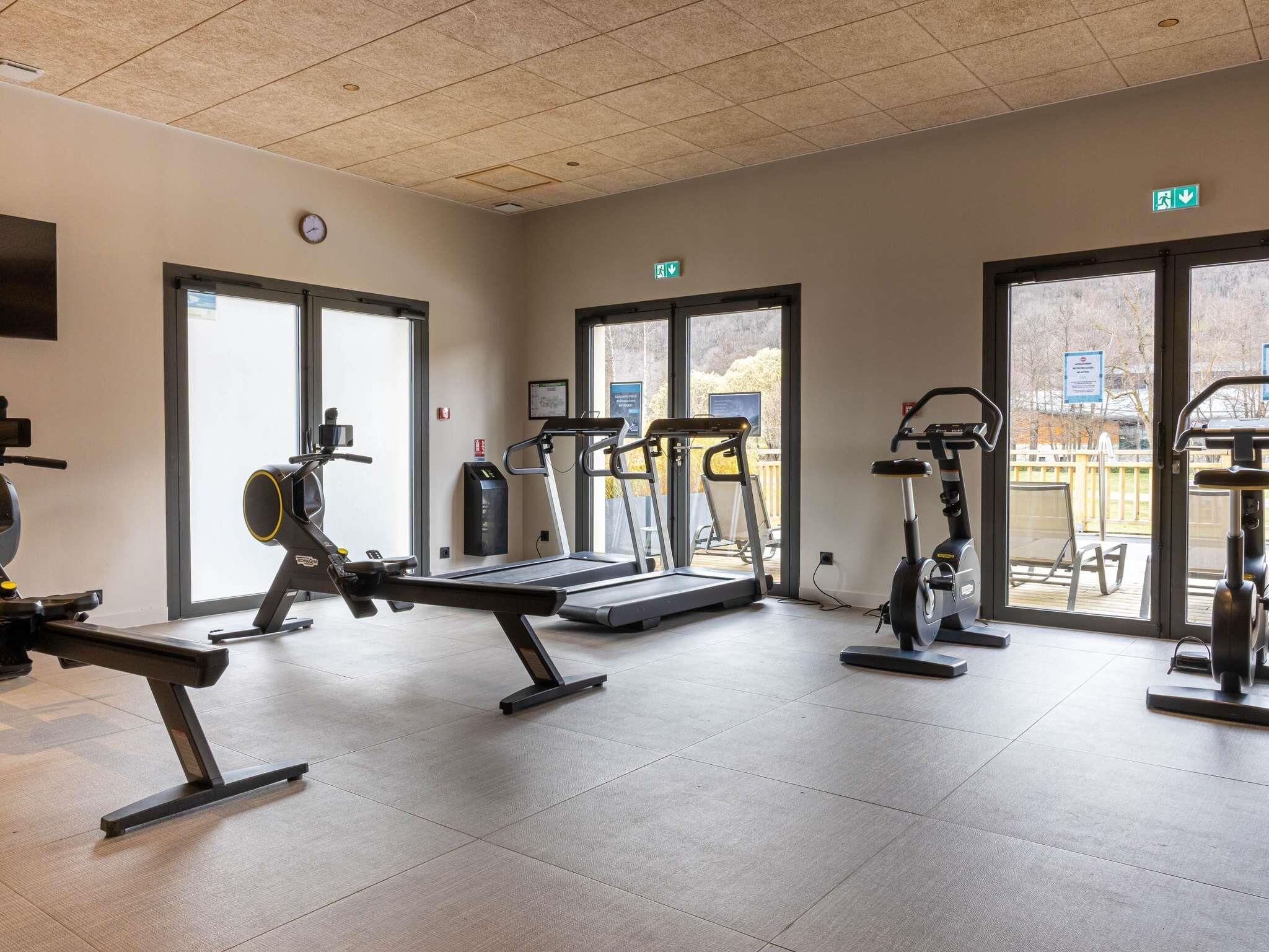 Une salle de sport équipée de tapis de course, de vélos elliptiques et de bancs de musculation.