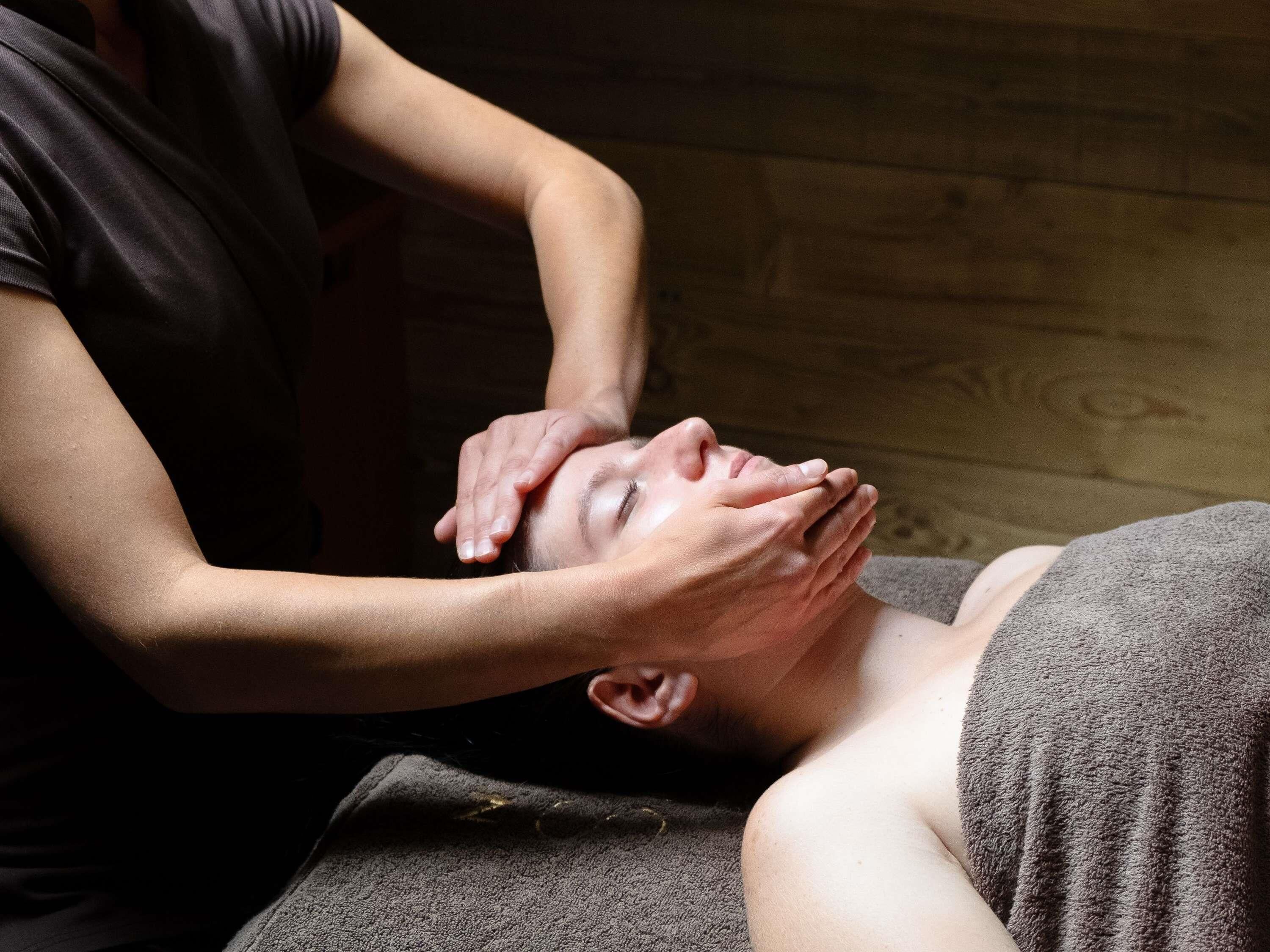 Iemand ontvangt een hoofdmassage in een kamer met houten wanden.