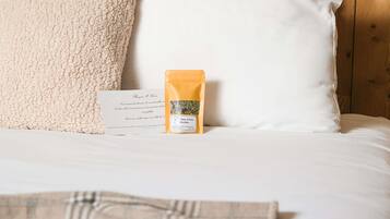 Una cama con almohadas blancas y una caja de té encima.