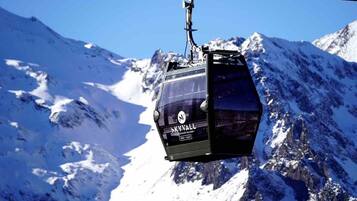 A cable car suspended over a snowy mountain landscape.
