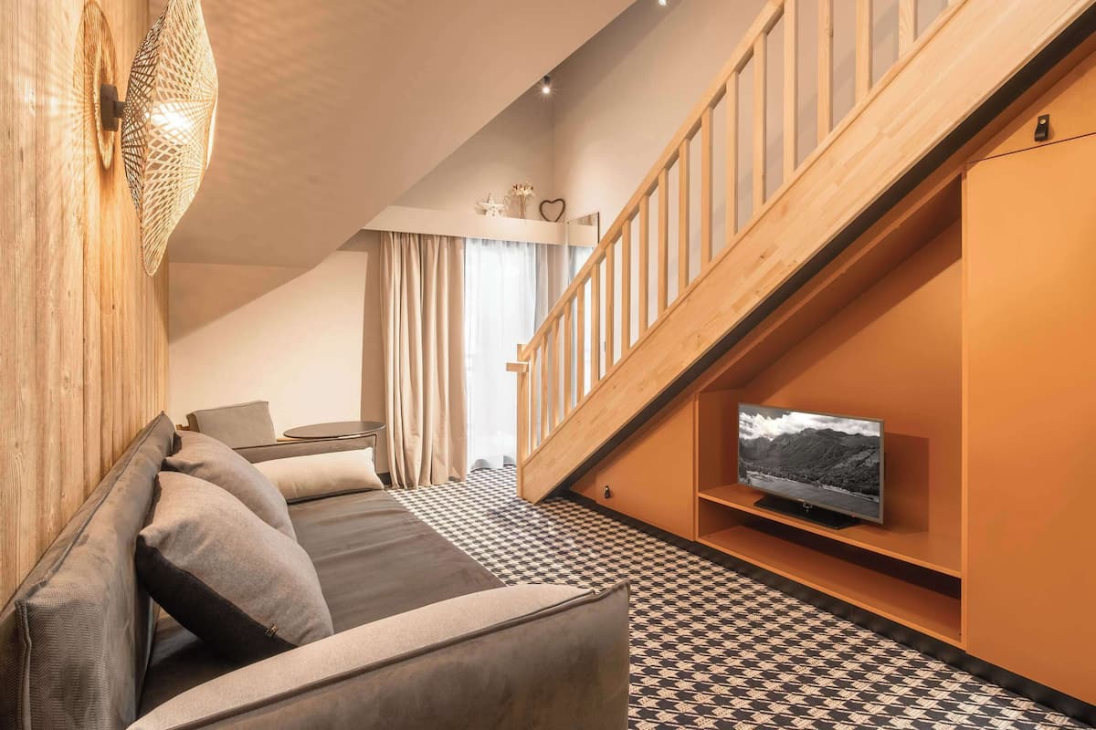 Cozy seating area with a sofa, side table, and mounted TV, plus a staircase leading to an upper level.