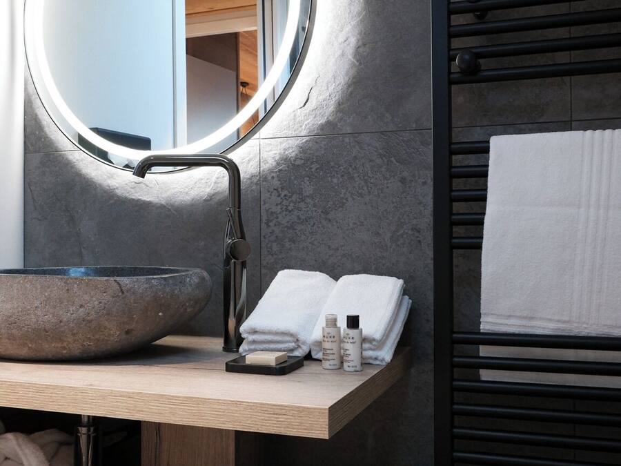 Un baño moderno con un espejo redondo, un lavabo y un perchero para toallas.