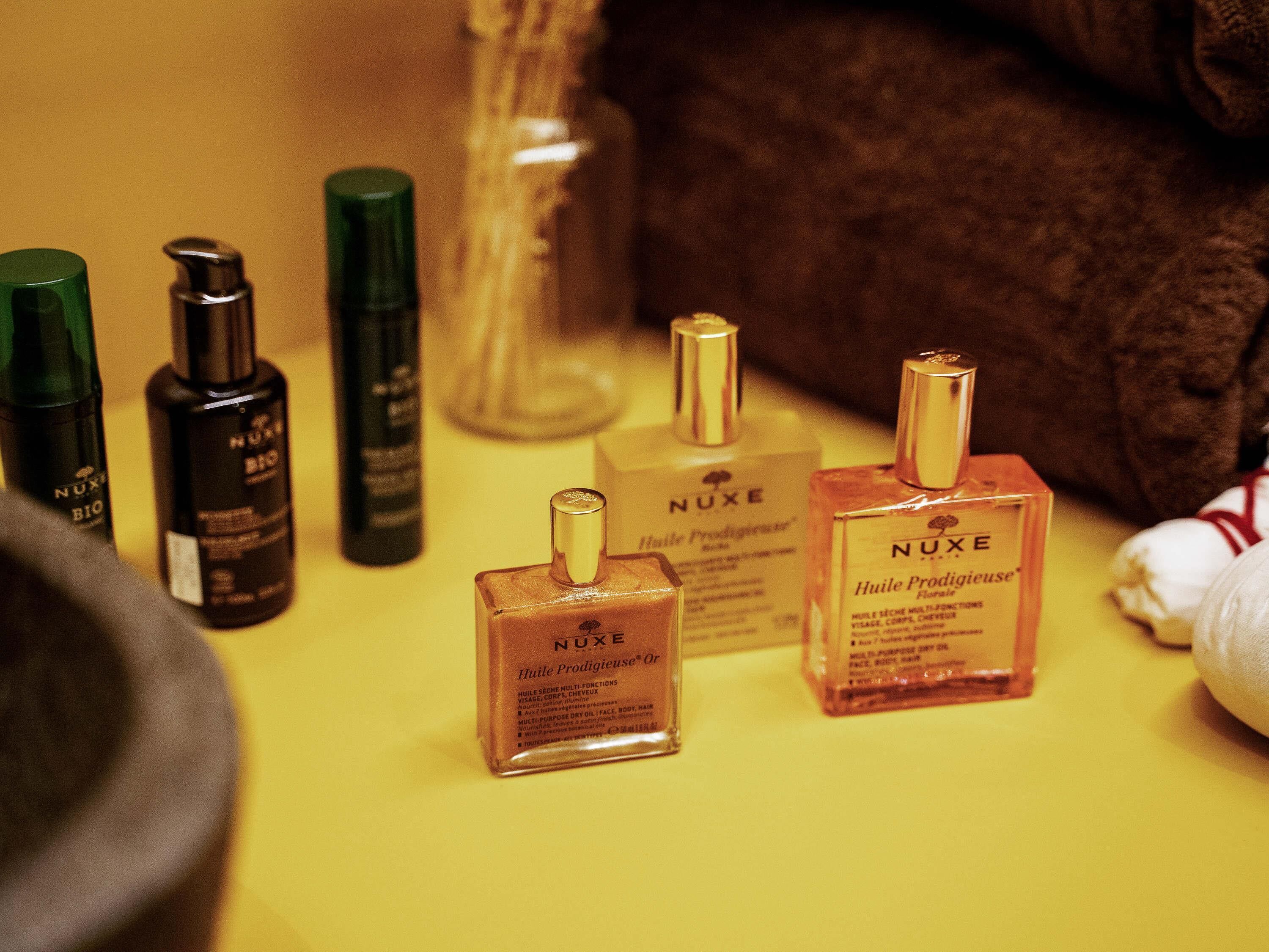 A collection of Nuxe skincare products on a yellow surface.