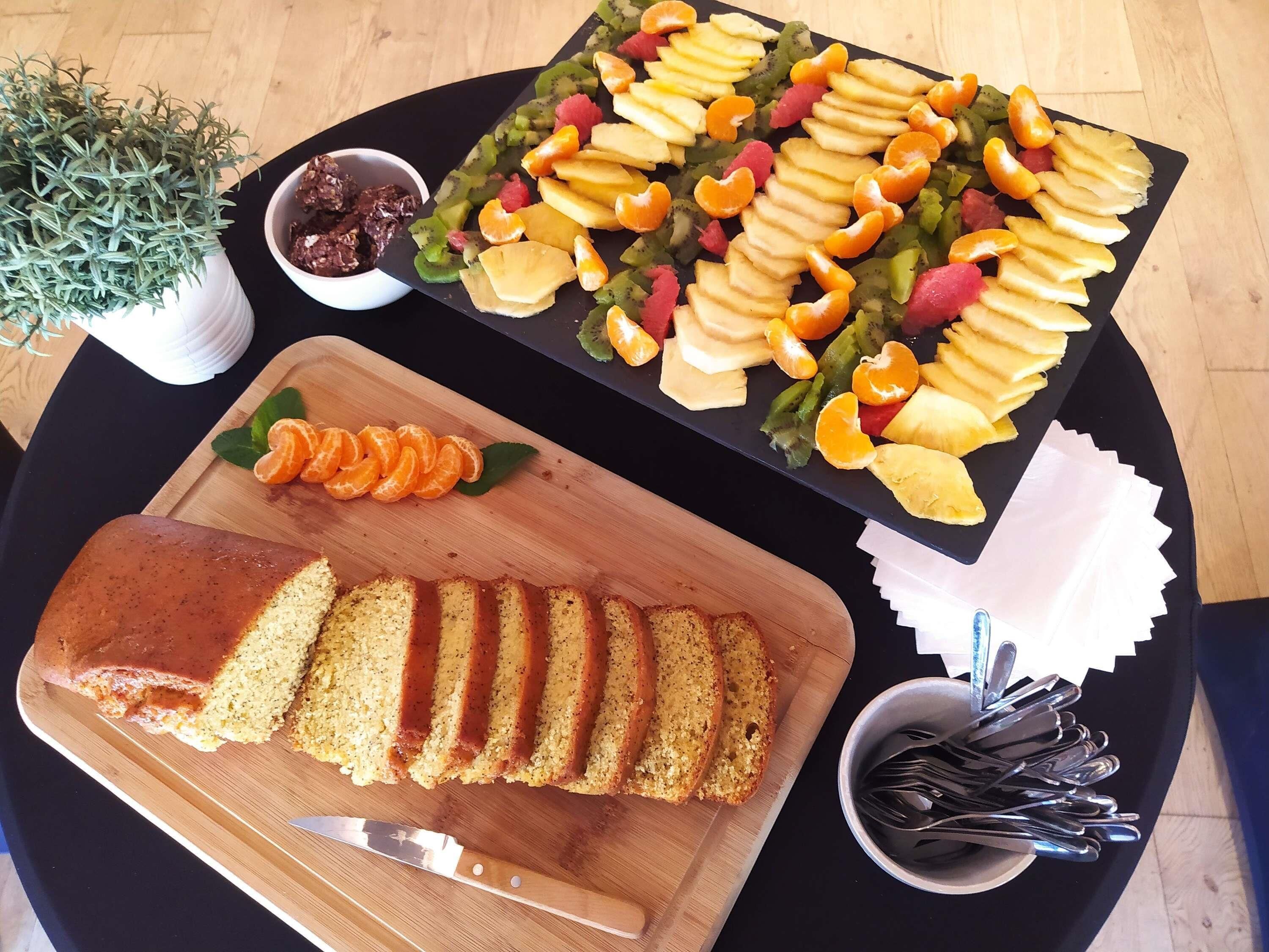 A table with a loaf of bread, a fruit platter, and a small bowl of jam.