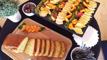 A table with a loaf of bread, a fruit platter, and a small bowl of jam.