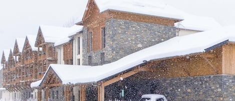 A snow-covered building with a stone facade and multiple pointed roofs, likely a hotel or lodge.