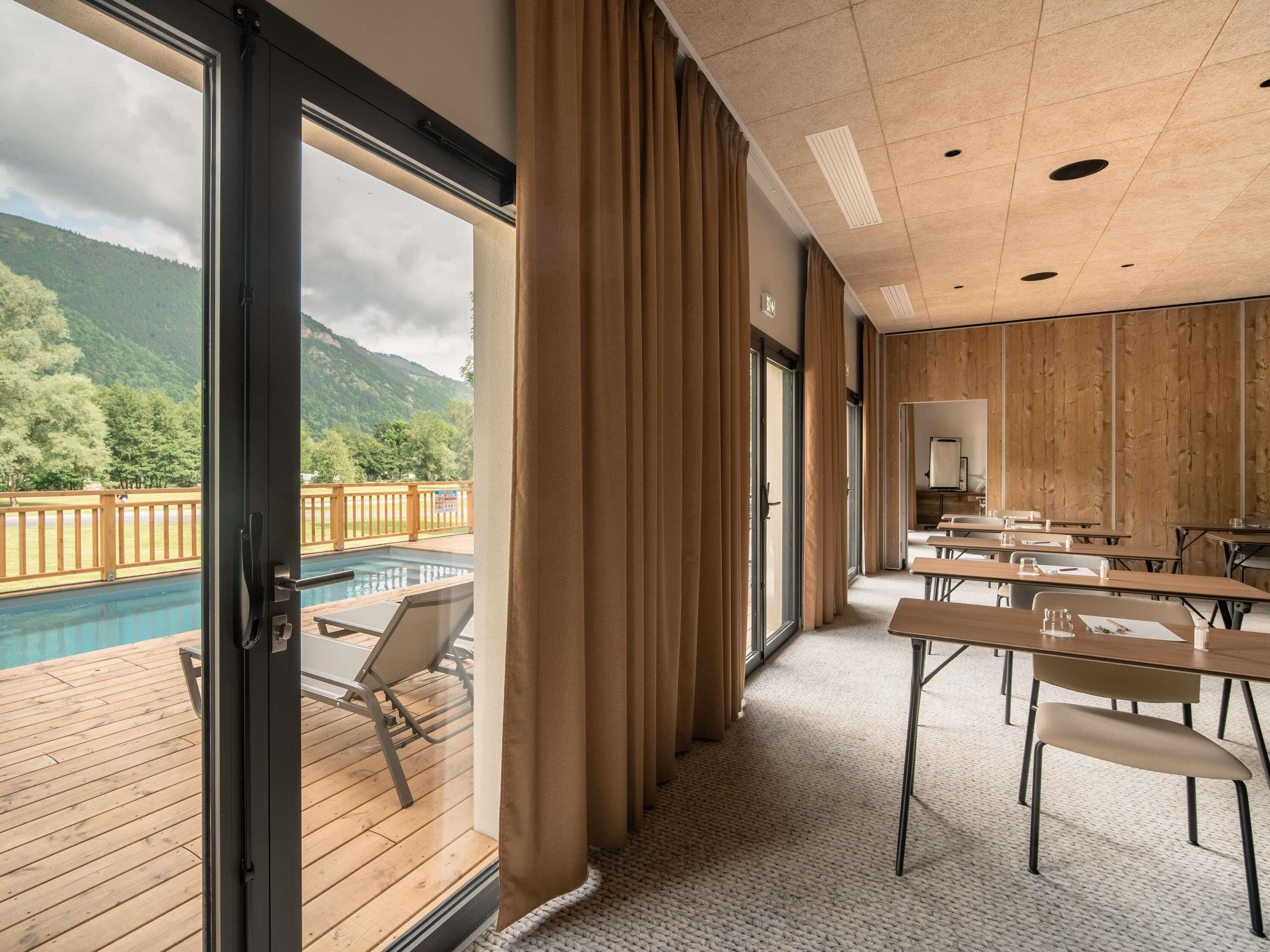 A room with a pool view, wooden panel walls, and a conference table.