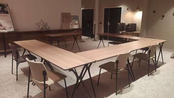 A conference room with long tables and chairs, a star decoration on the wall, and a door in the background.