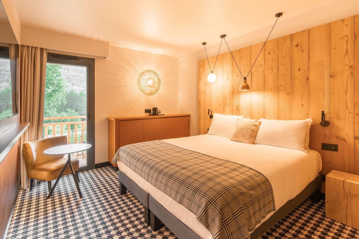 Une chambre à coucher avec un lit, une chaise, une petite table et un mur en bois.