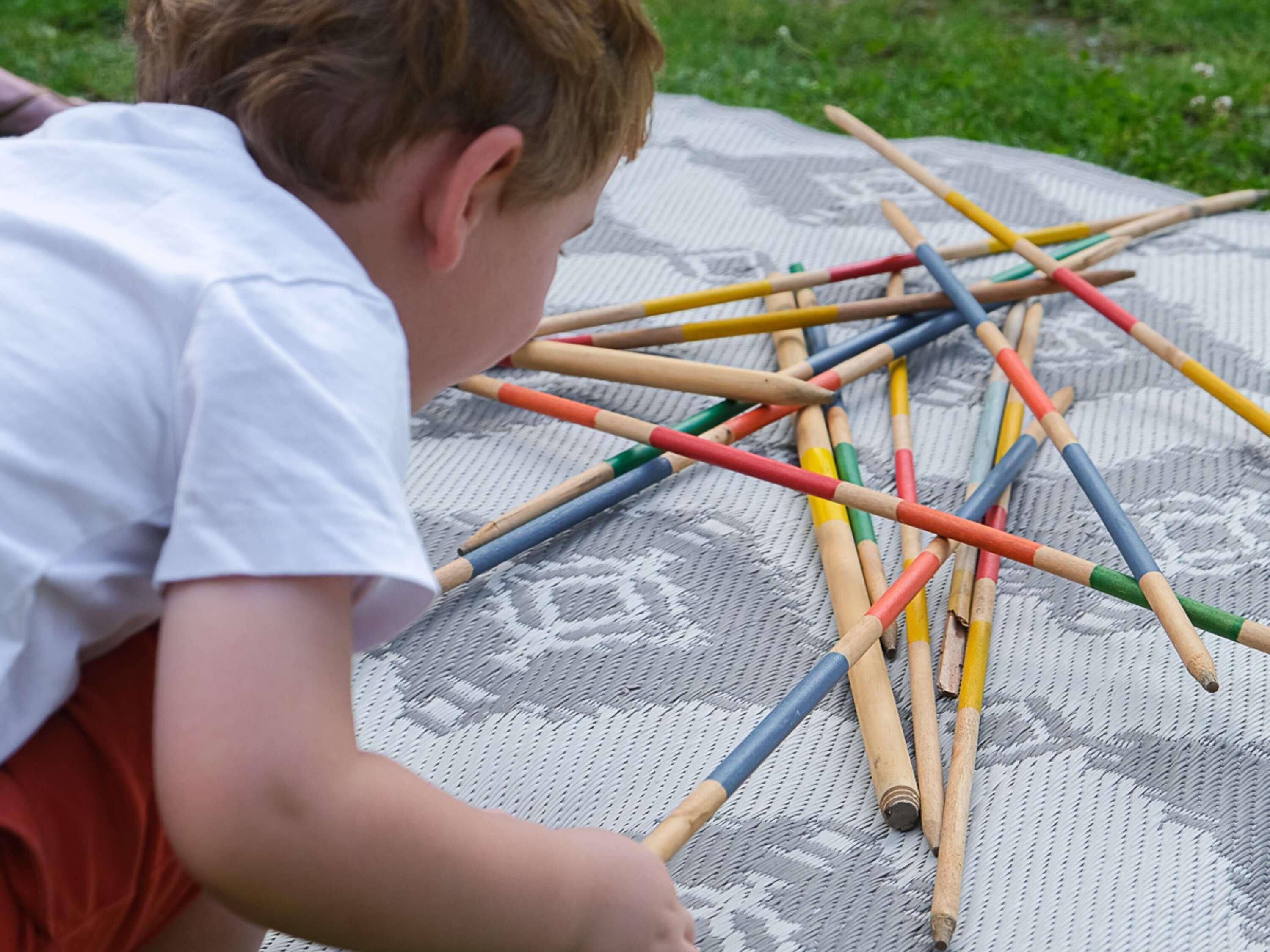 Niño jugando con palitos de colores sobre un tapete estampado.