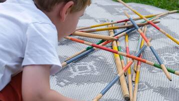 Niño jugando con palitos de colores sobre un tapete estampado.