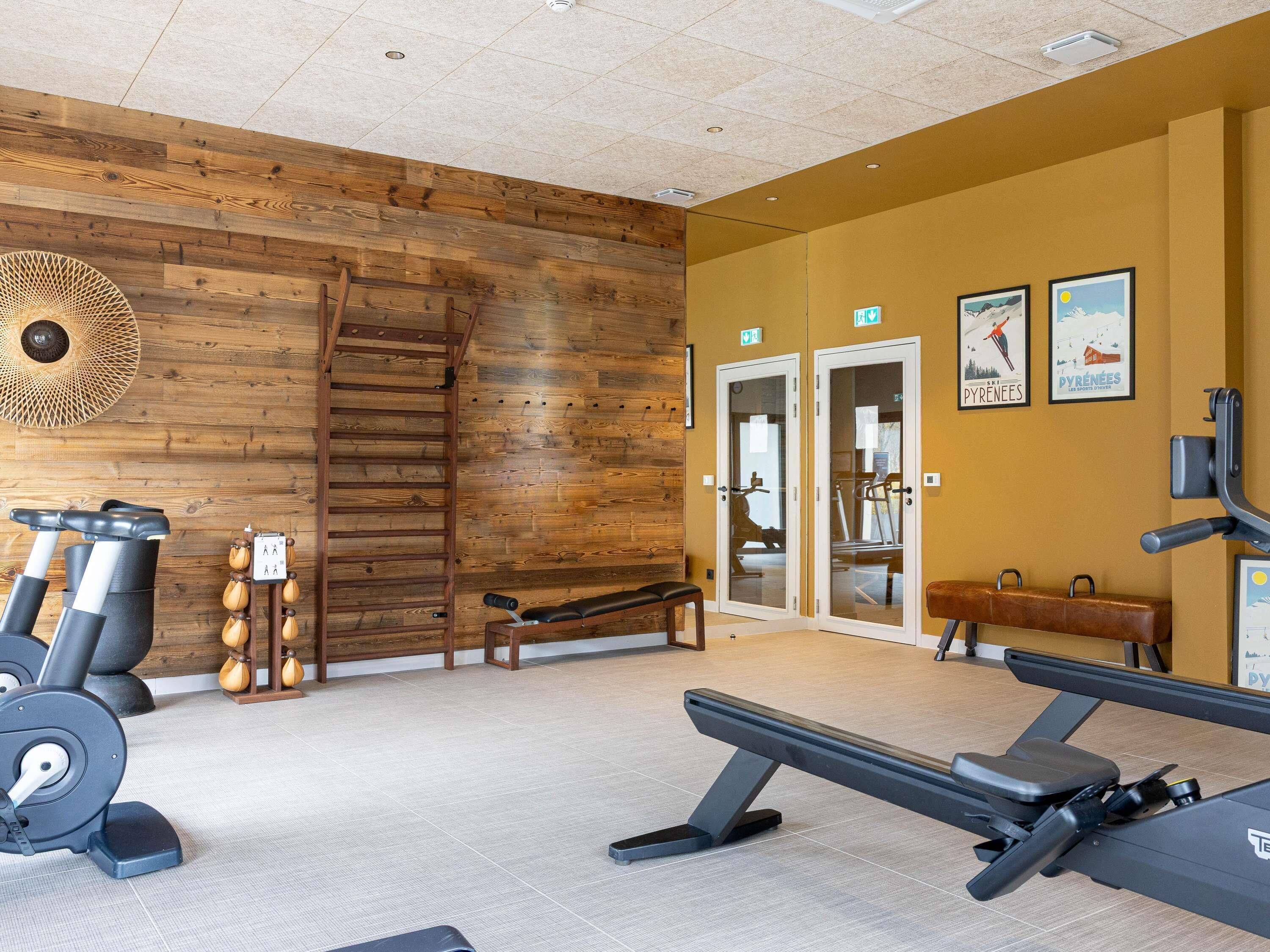 Un gimnasio con equipo de ejercicio, un muro de madera y una banca.