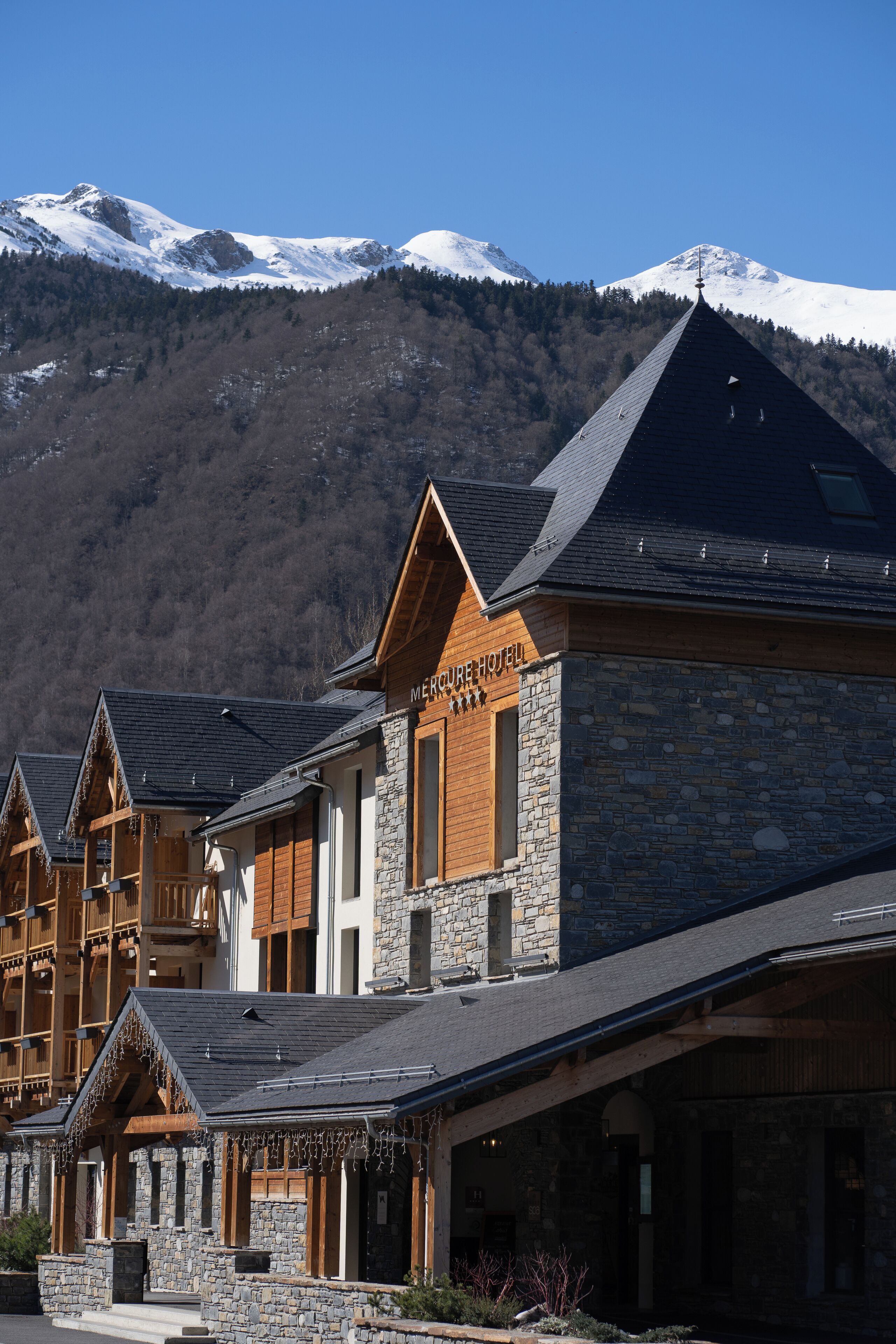Un hotel de arquitectura de piedra y madera, con un letrero destacando.