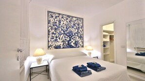 A hotel room with a bed, bedside tables, a wall-mounted artwork, a wardrobe, and a mirror.