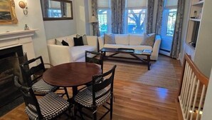 Uma sala de estar espaçosa, com mesa e cadeiras de jantar, sofá e ventoinha no teto.