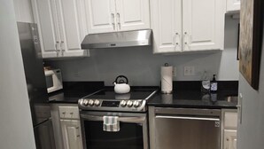 Uma cozinha moderna com armários brancos, fogão de aço inoxidável, micro-ondas e lava-louças.