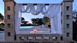 A concrete structure with draped fabric, a pool, lounge chairs, and candles. - Trullo Don Mino, near Alberobello and Locorotondo, private pool (Locorotondo)