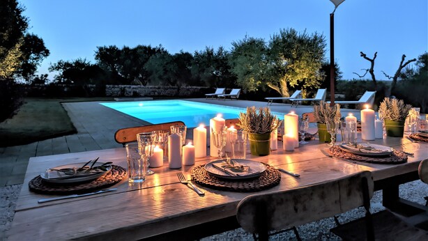 An outdoor dining area with a pool, candles, and a table set for a meal. - Trullo Don Mino, near Alberobello and Locorotondo, private pool (Locorotondo)