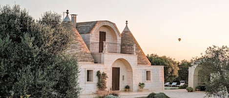 A stone building with a turreted roof, arched doorways, and a balcony.
