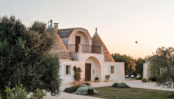 A stone building with a turreted roof, arched doorways, and a balcony. - Trullo Don Mino, near Alberobello and Locorotondo, private pool (Locorotondo)