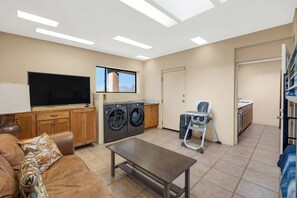 A living room with a sofa, a coffee table, a TV, a washing machine, and a chair.