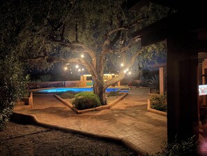 An outdoor pool area with a tree, seating, and a building in the background. - Saguaro Retreat-Salt Pool, Spa, Mountain Views (Tucson)