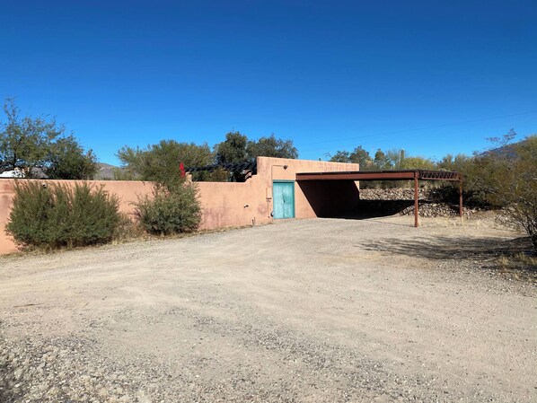 A building with a blue door, a covered outdoor area, and a gravel driveway.